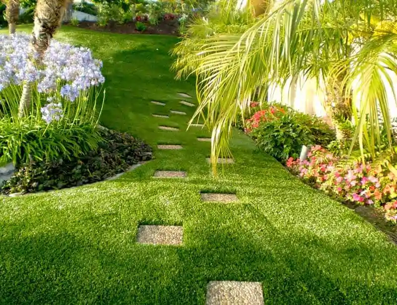 Jardim paisagístico com grama sintética e caminho de pedras